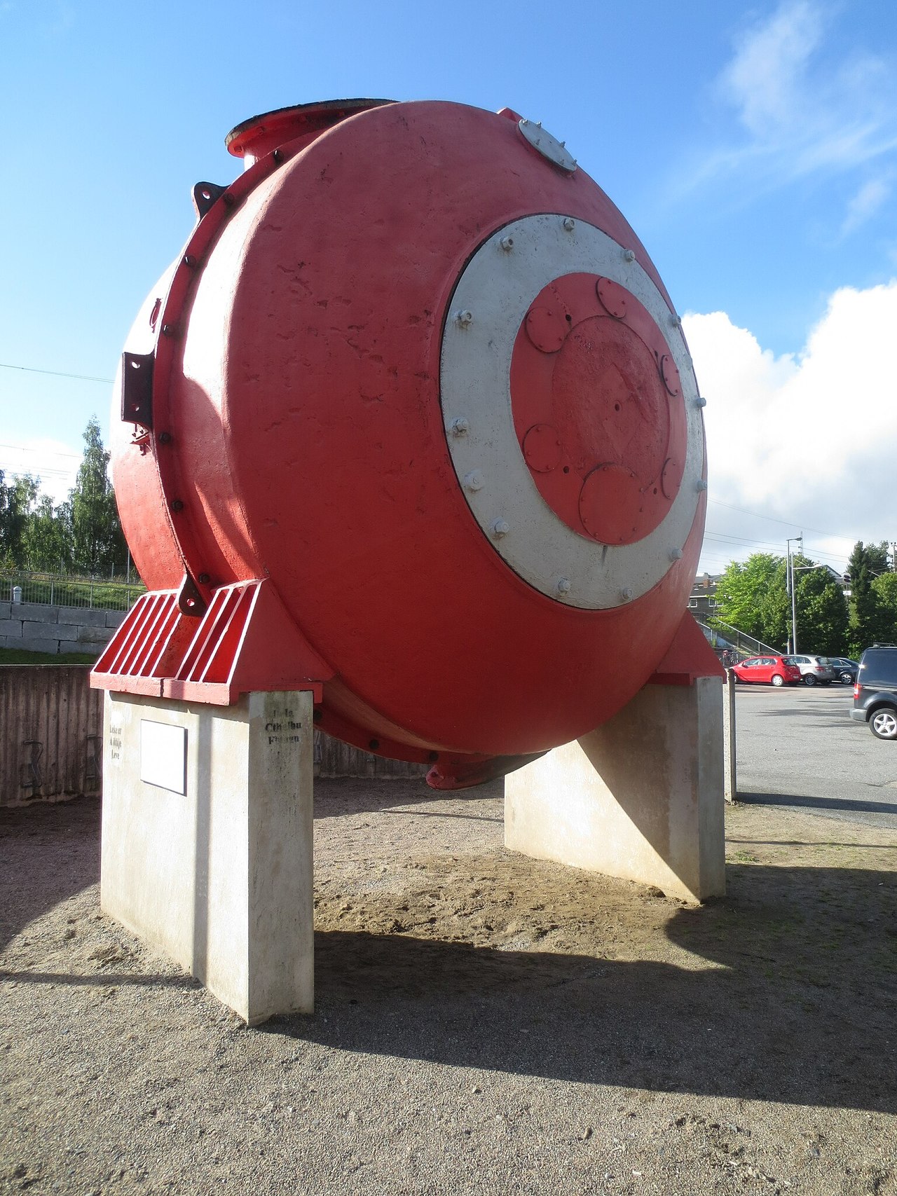 Stor tønneformet industriovn i metall, rødfarget på betongfundament