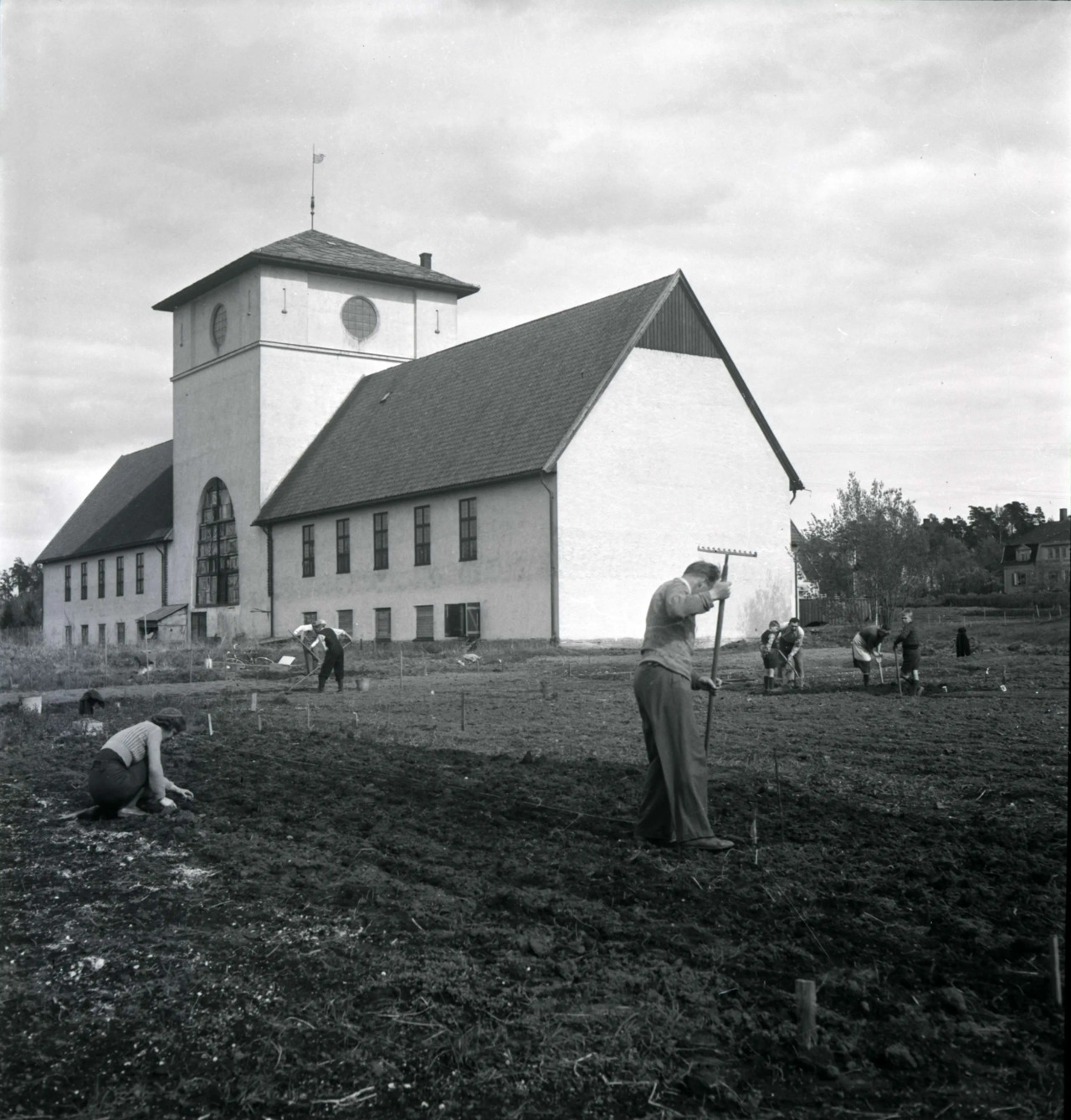 Vikingskipshuset i bakgrunnen. Flere personer arbeider med å klargjøre jordsmonnet for dyrking