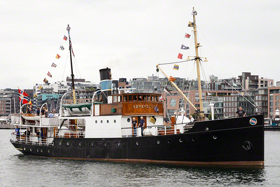 Dampskipet i Oslo havn. Svart skrog med runde koøyer. Brohuset i mørkt trepanel med navnet i messingbokstaver