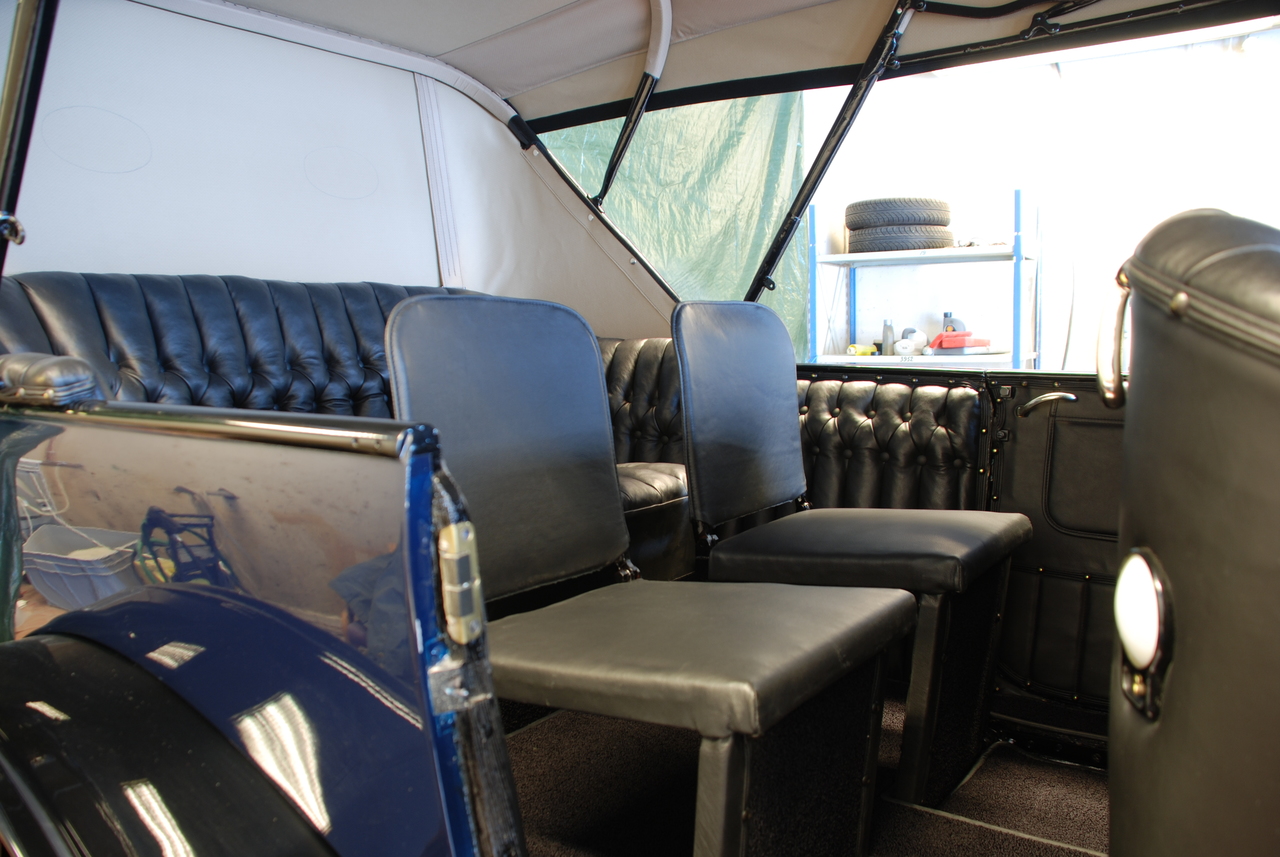 Baksetet. Knappepolstringen fortsetter fra sofaen og videre fram på siden av klappstolene